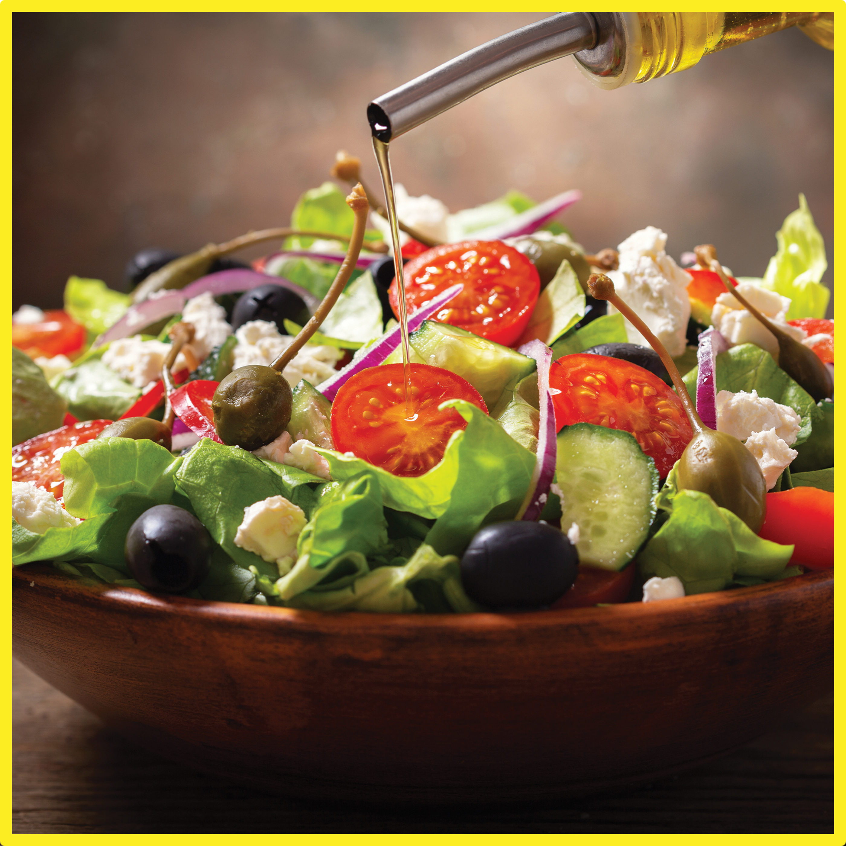 summer Greek salad in a bowl being drizzled with olive oil