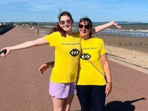 Nancy and her daughter smiling and hugging in Macular Society shirts at the beach