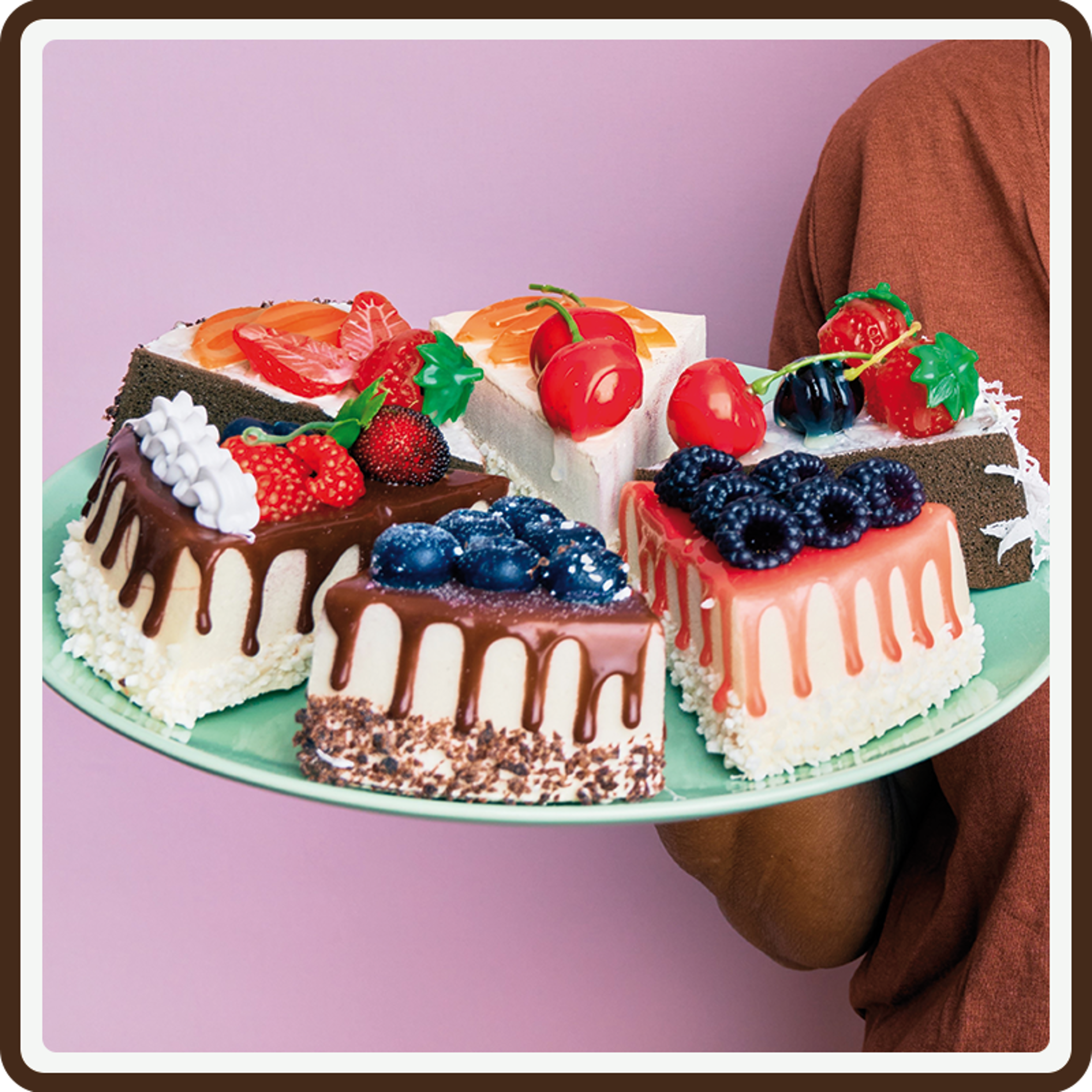 A blue plate with a variety of decorated cake slices with a pink backdrop