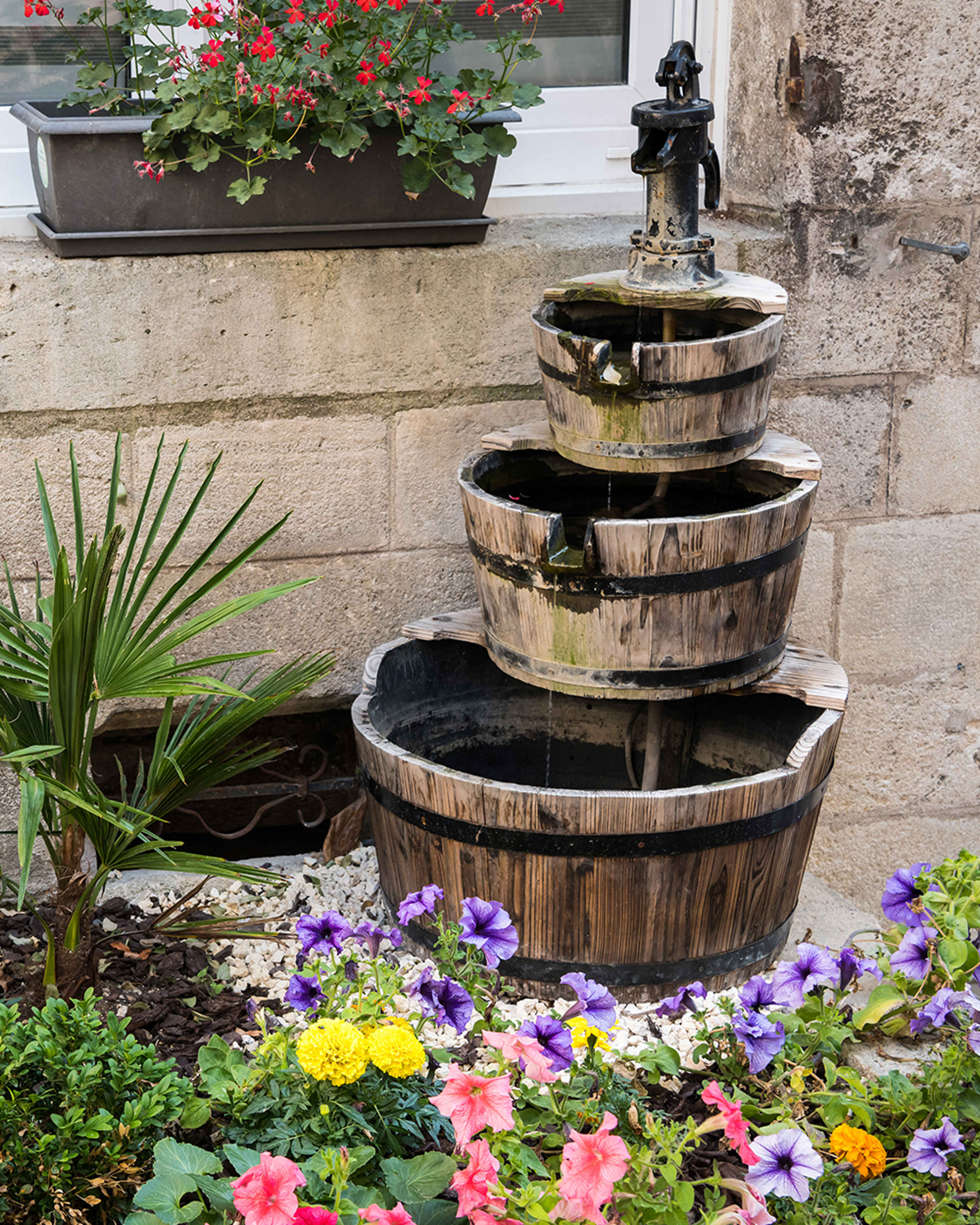 A wooden water feature in a garden surrounded by flowers