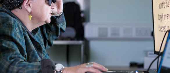A female patient taking part in the PRIMA System clinical trial, using the device to read letters on a computer screen.